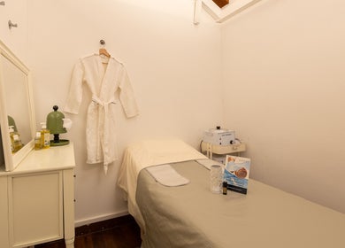 Relaxing spa room at Roses & More Skin Alchemy, Singapore, SG, with treatment bed and robe.