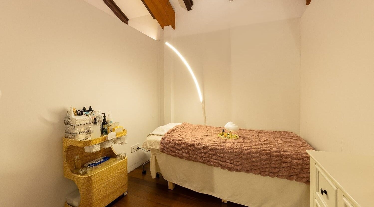 Tranquil treatment room at Roses & More Skin Alchemy, Singapore, SG with cozy bed and ambiance lighting.