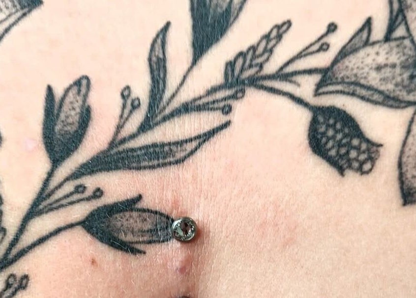 Floral tattoo with dermal piercing at Elysian Beauty and Piercing in Sudbury, GB.