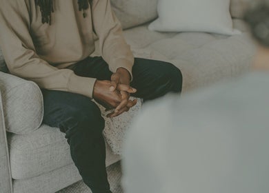 Individual sitting on a cozy couch at Mindful Moments wellness Hub, Johannesburg, ZA, promoting relaxation.