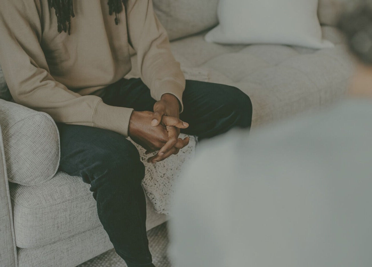 Individual sitting on a cozy couch at Mindful Moments wellness Hub, Johannesburg, ZA, promoting relaxation.