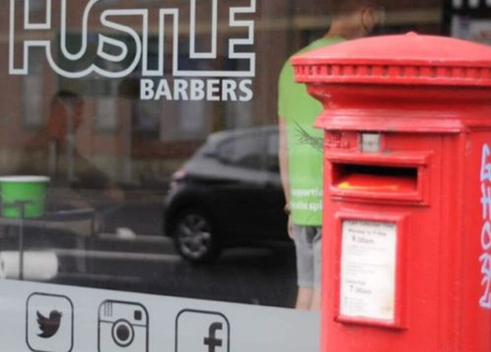 Hustle Barbers storefront with a classic red postbox in Chesterfield, England, GB.
