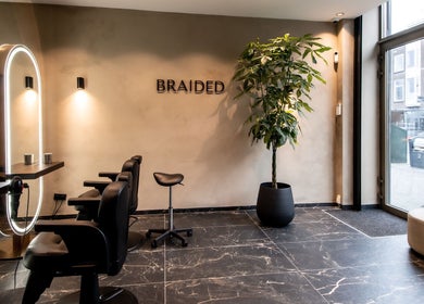 Moderne saloninrichting bij Braided in Arnhem, Gelderland, NL met stijlvolle stoelen en groene plant.