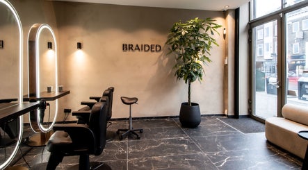 Moderne saloninrichting bij Braided in Arnhem, Gelderland, NL met stijlvolle stoelen en groene plant.