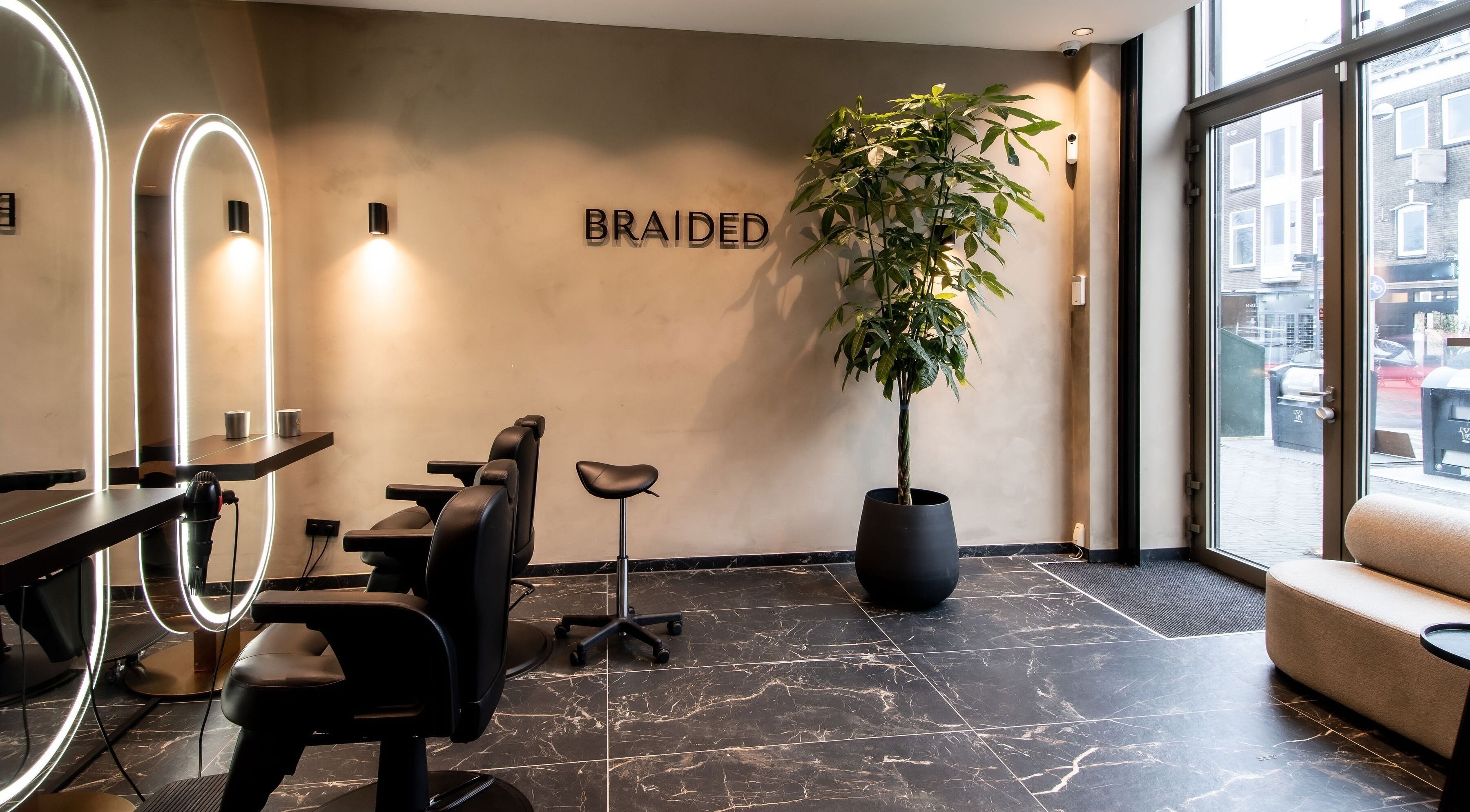 Moderne saloninrichting bij Braided in Arnhem, Gelderland, NL met stijlvolle stoelen en groene plant.
