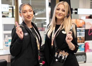 Friendly staff at Boots beauty counter in Beccles, England, GB, showcasing makeup tools.