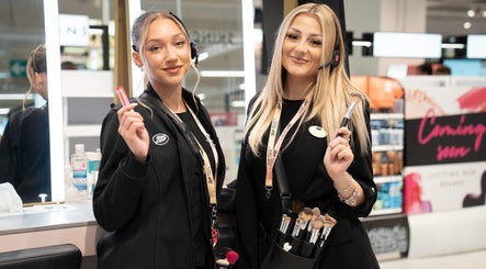 Friendly staff at Boots beauty counter in Beccles, England, GB, showcasing makeup tools.