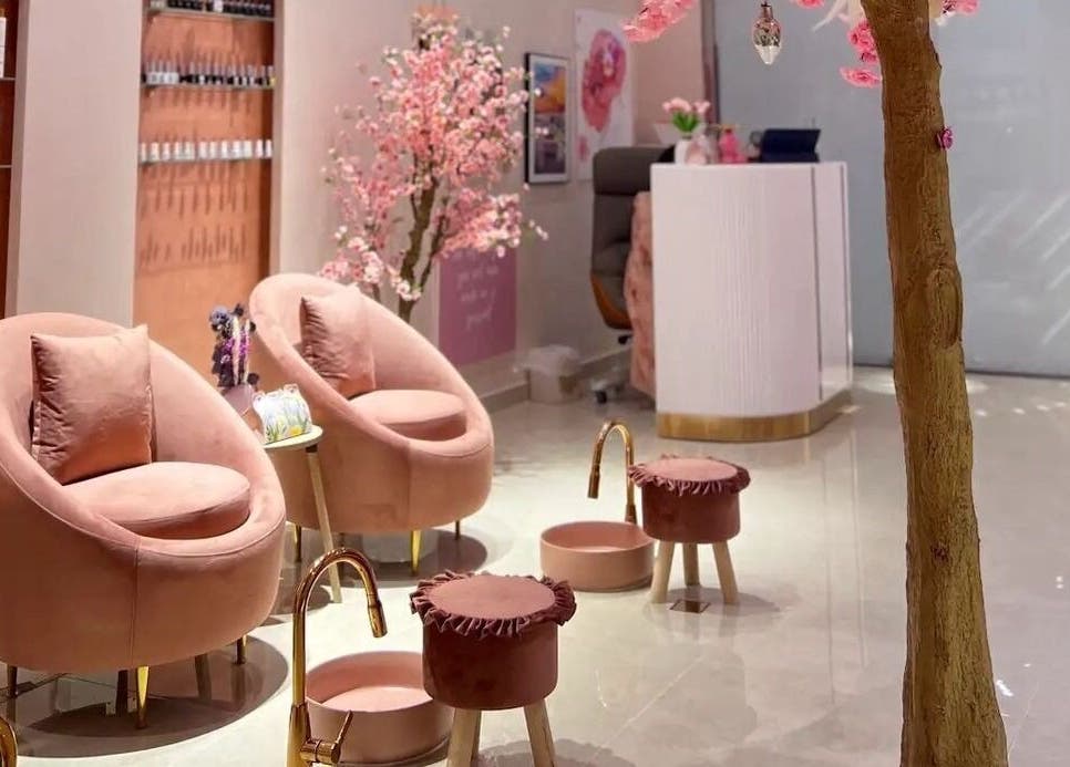 Elegant interior of High End Details Beauty Salon in Sharjah with plush pink seating and cherry blossoms.