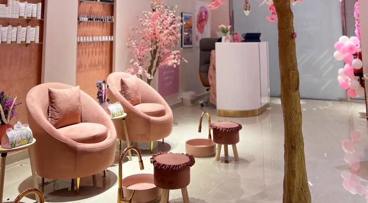 Elegant interior of High End Details Beauty Salon in Sharjah with plush pink seating and cherry blossoms.