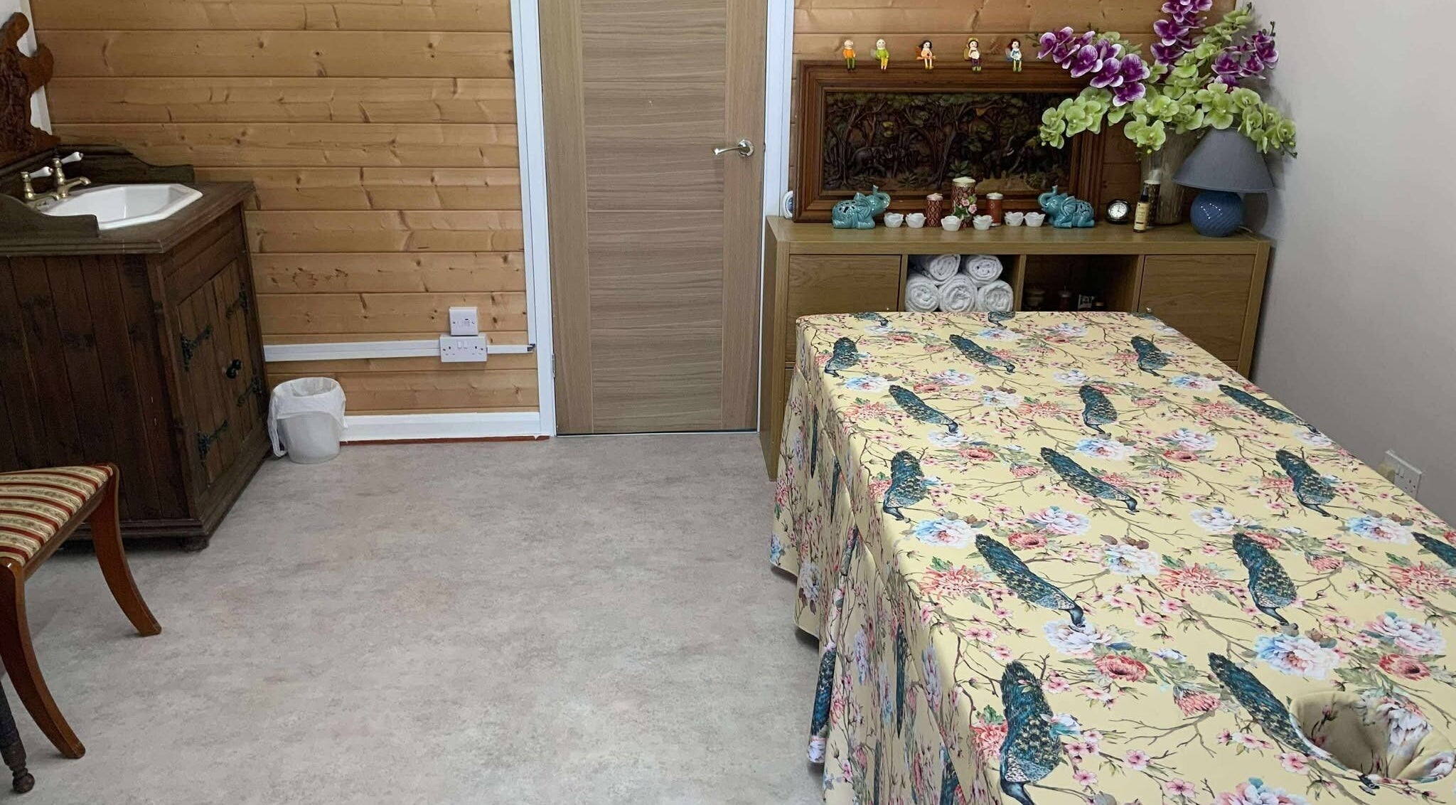 Cozy therapy room at Oak Barn Thai Massage in Lingfield, Newchapel, England, GB with floral decor and wooden accents.