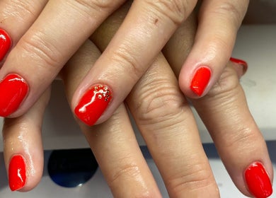 Vibrant red nails with gold accents at Nu Nails And Beauty, Hemel Hempstead, England, GB.