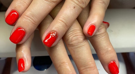 Vibrant red nails with gold accents at Nu Nails And Beauty, Hemel Hempstead, England, GB.