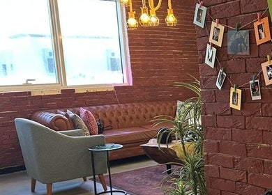 زاوية جلوس مريحة في Gurls & Curls بالرياض، منطقة الرياض، SA مع أريكة جلدية وجدار من الطوب.