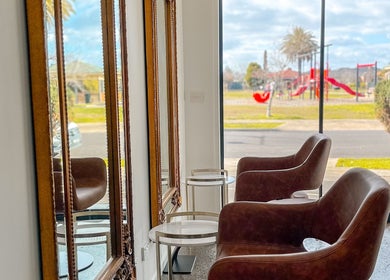 Stylish seating and mirrors at Renz Hair Studio, Melbourne, Victoria, AU, with a bright view outside.