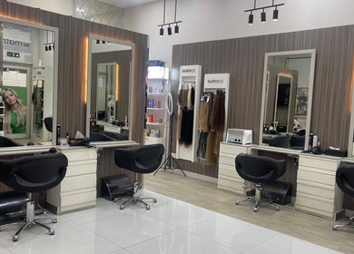 Modern salon interior at Dreams Salon, Dubai, AE, featuring stylish chairs and large mirrors.