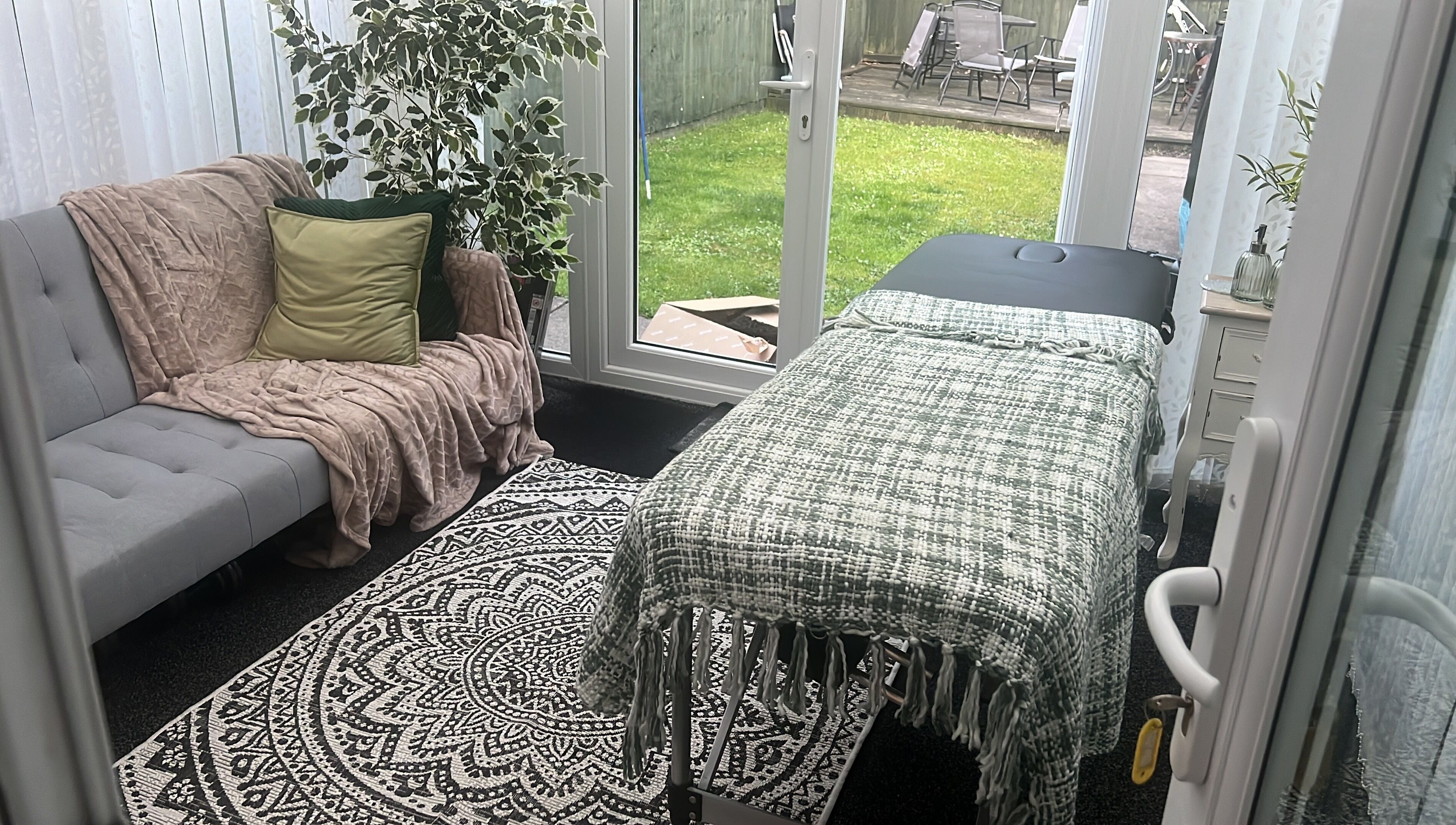 Stylish therapy room in The Zen Den, Whitworth, England, GB with comfy sofa and massage table.
