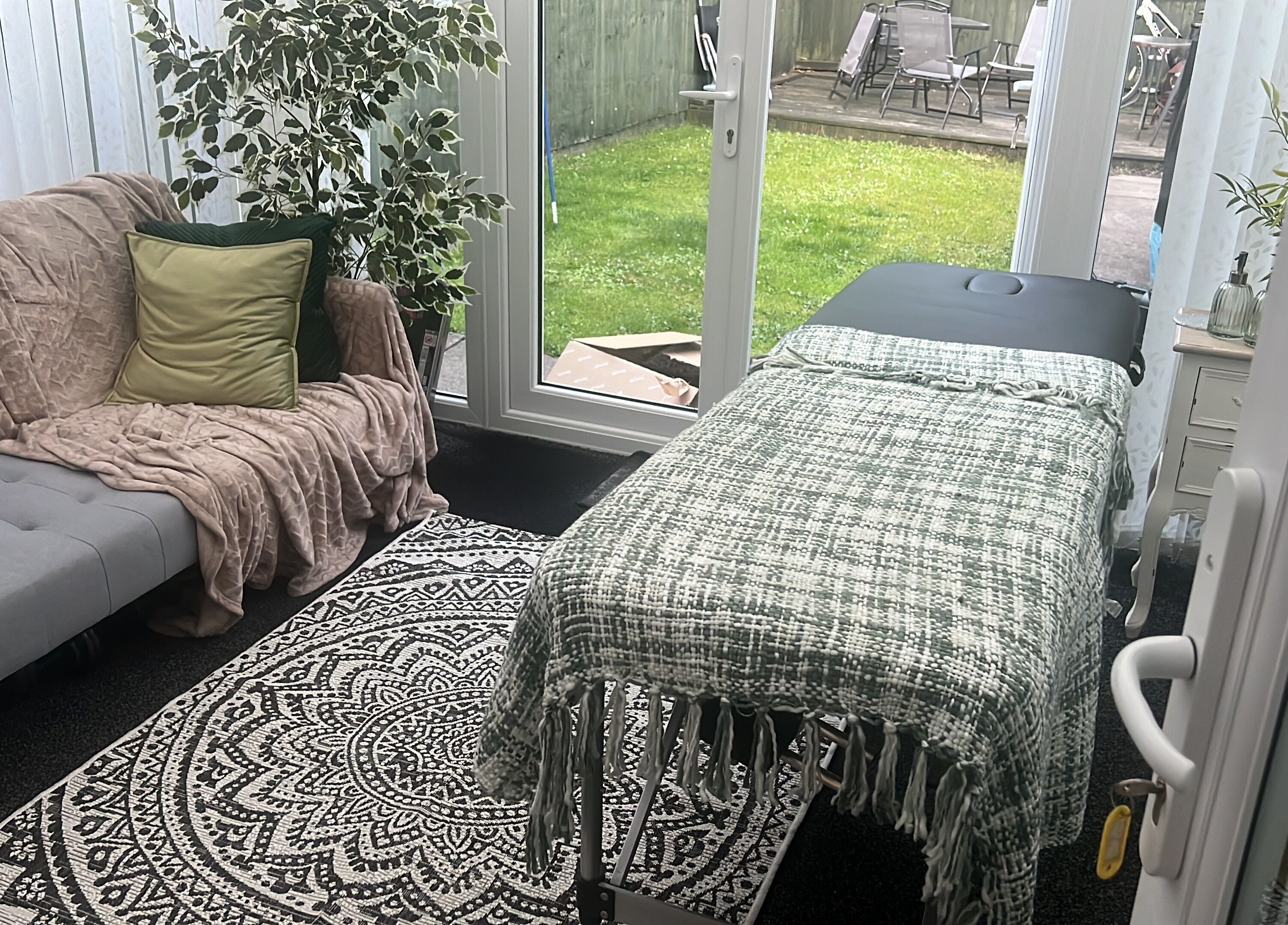 Stylish therapy room in The Zen Den, Whitworth, England, GB with comfy sofa and massage table.