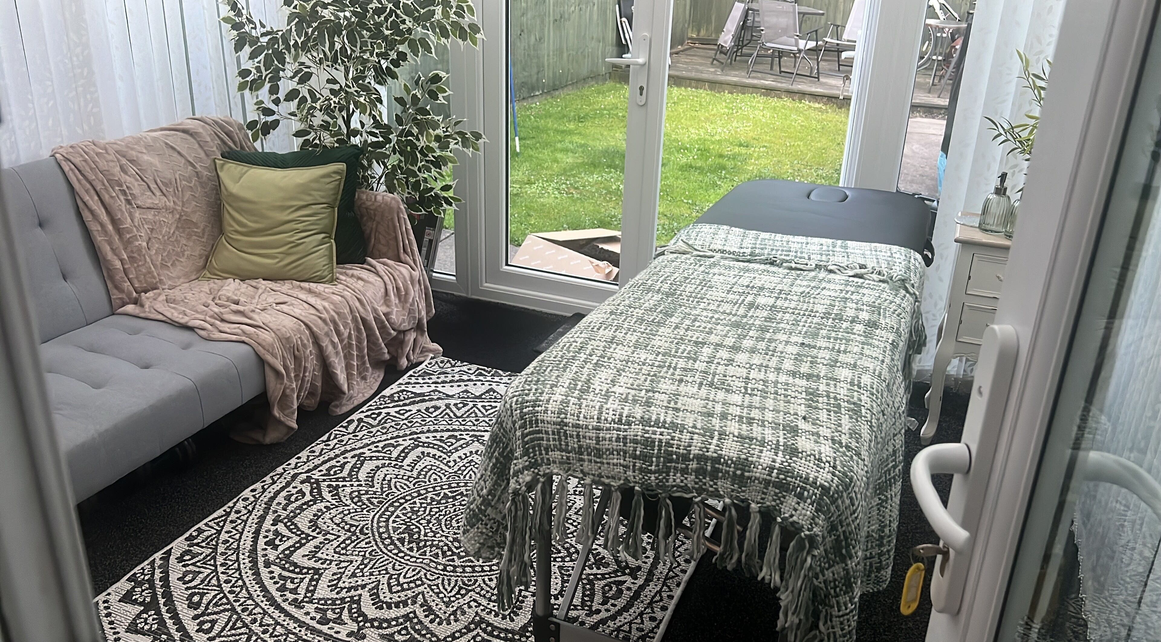 Stylish therapy room in The Zen Den, Whitworth, England, GB with comfy sofa and massage table.
