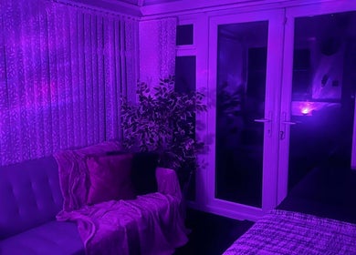 The Zen Den in Whitworth, England, GB features a serene room with purple lighting, plush seating, and a calming ambiance.