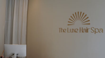 Reception area at The Luxe Hair Spa in Barcelona, Catalunya. Minimalist design with logo in gold.