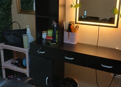 Stylish salon desk at Infinite Finesse by Chanel, Saint George's, GD, with beauty essentials and a lit mirror.