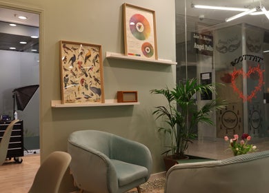 Intérieur élégant du studio Fleur de Peau Tattoo, Courbevoie, avec des affiches artistiques et des fauteuils confortables.