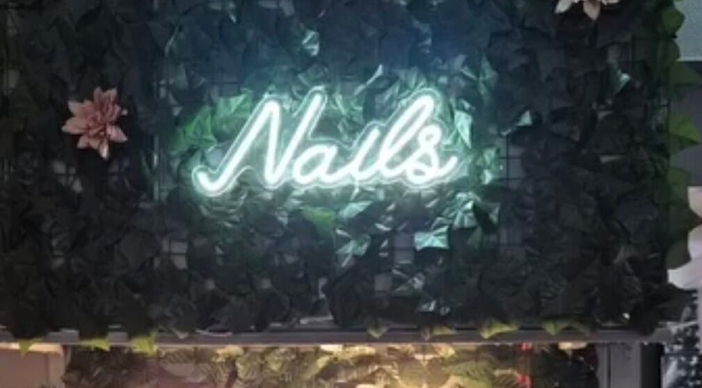 Neon sign reads 'Nails' at Simply Luxe Beauty, a chic salon in Coatbridge, Scotland, GB with floral decor.