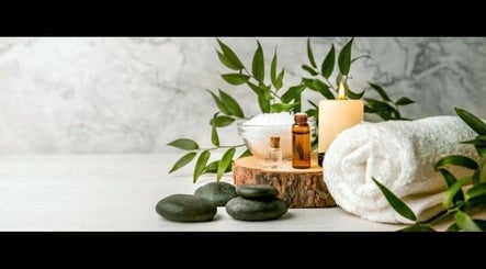 Spa essentials at Simply Luxe Beauty in Coatbridge, Scotland, GB, featuring stones, towel, candle, and foliage.