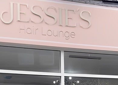 Front view of Jessie's Hair Lounge, Whaley Bridge, England. Elegant pink sign above glass entrance.
