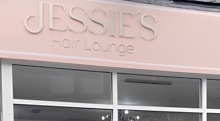 Front view of Jessie's Hair Lounge, Whaley Bridge, England. Elegant pink sign above glass entrance.