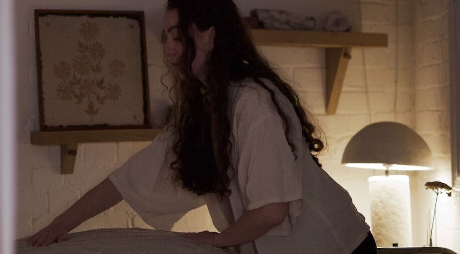 Therapist preparing a treatment room at Alchème Sanctuary, London, England, GB for a calming session.