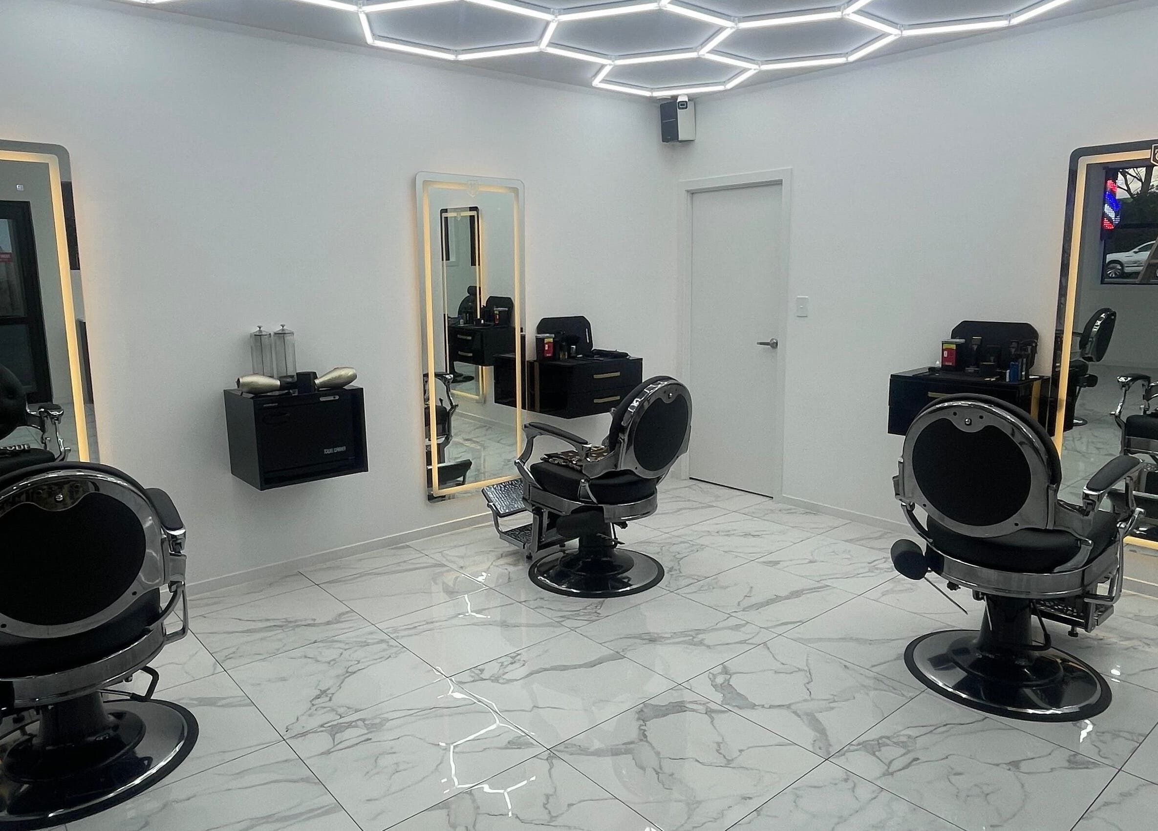 Modern interior of Crwn Barbers in Auckland, NZ featuring sleek barber chairs and illuminated mirrors.