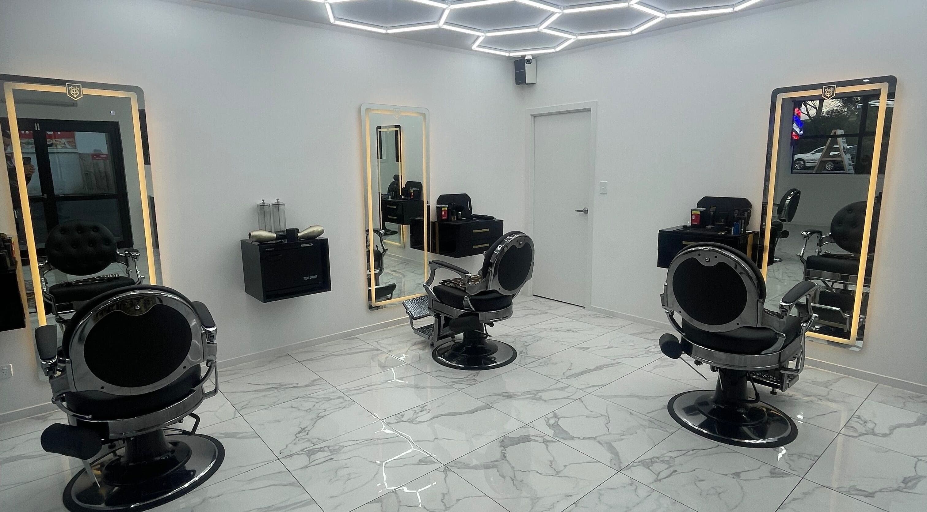 Modern interior of Crwn Barbers in Auckland, NZ featuring sleek barber chairs and illuminated mirrors.