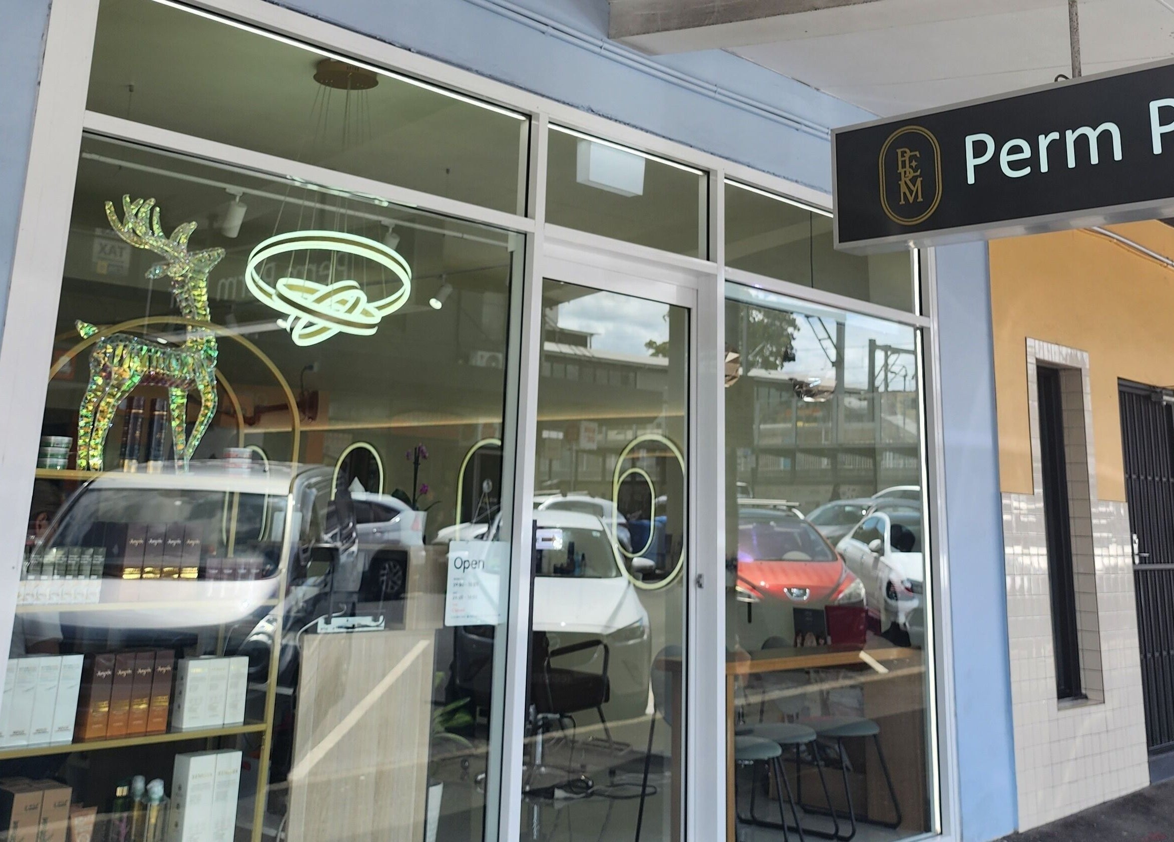 Perm Perm Hair's stylish facade in Lidcombe, New South Wales, AU, featuring modern signage and glass windows.