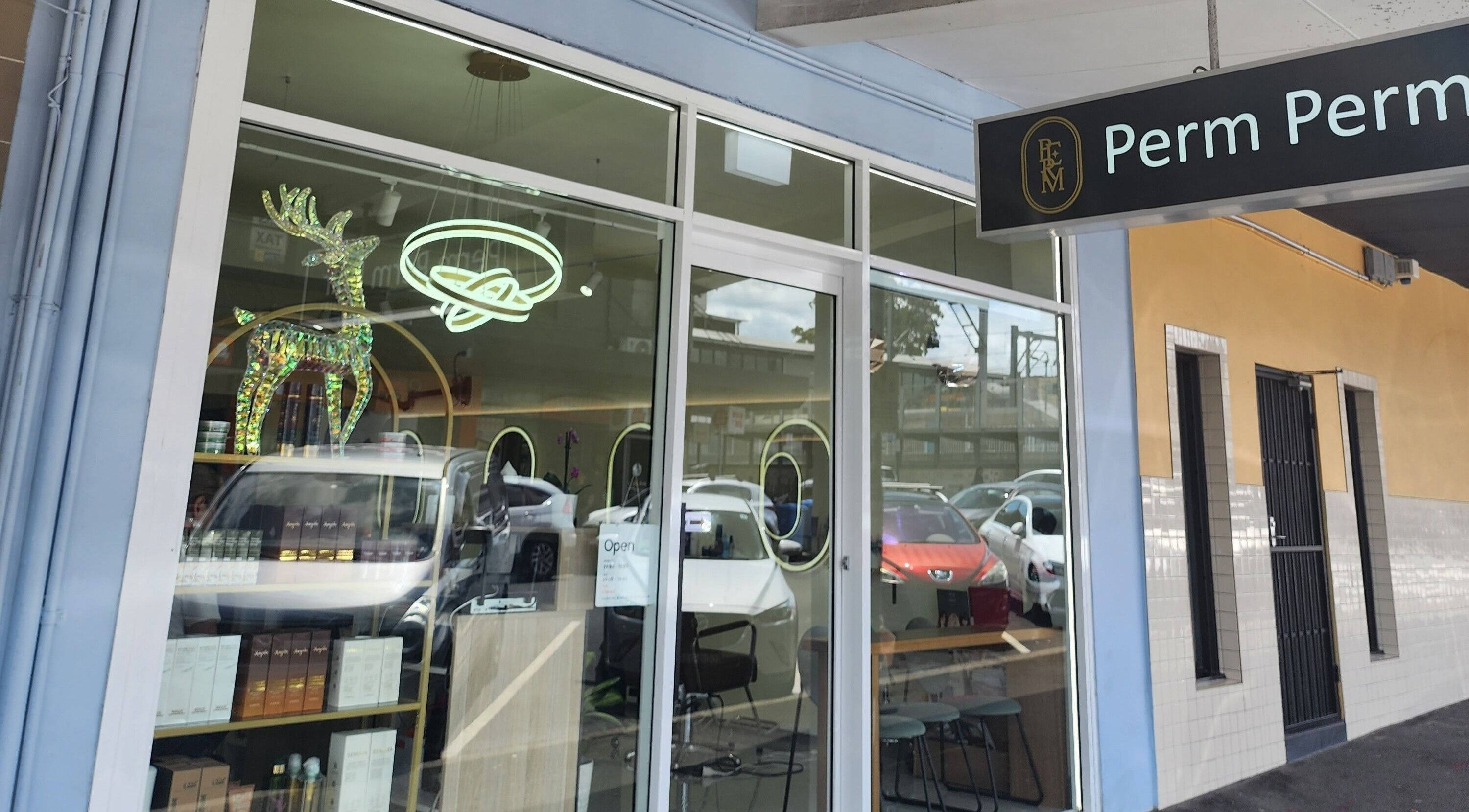 Perm Perm Hair's stylish facade in Lidcombe, New South Wales, AU, featuring modern signage and glass windows.