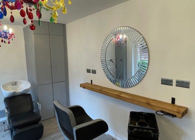 Elegant salon station at Eagle House Salon in Southwell, England, GB with vibrant chandelier and round mirror.