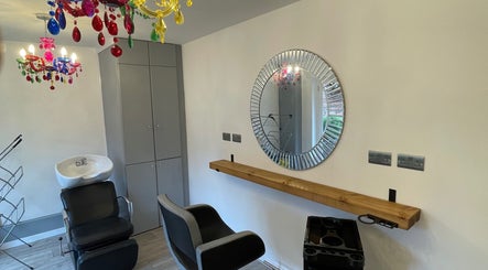 Elegant salon station at Eagle House Salon in Southwell, England, GB with vibrant chandelier and round mirror.