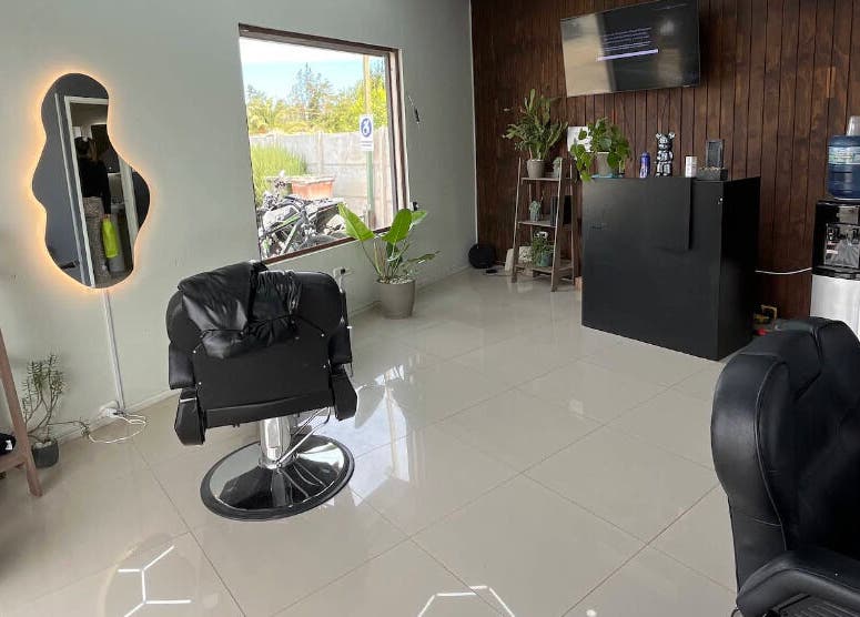 Interior moderno de Blood Studio en Cachapoal, O'higgins, CL con sillas negras y espejo iluminado.