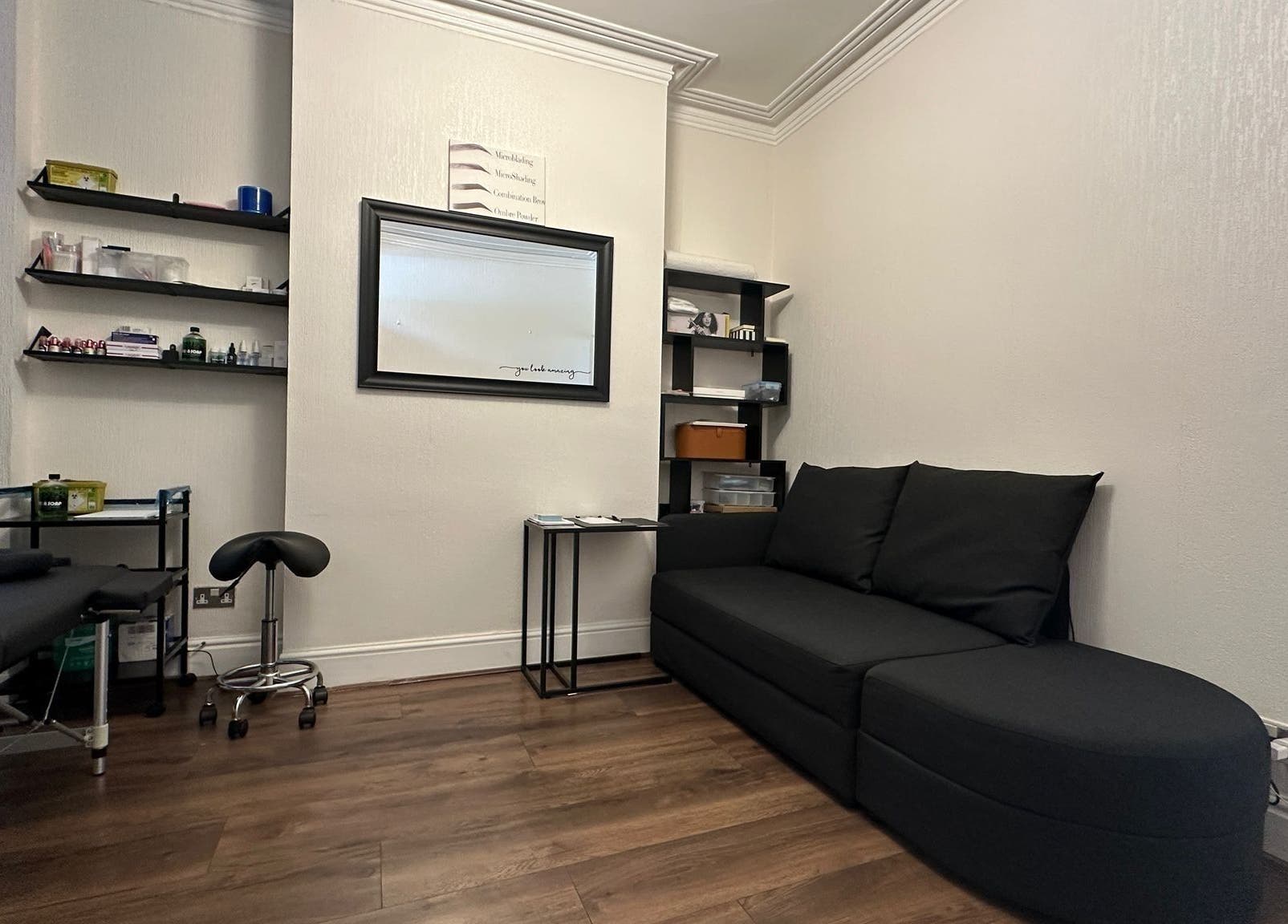 Cozy treatment room at Studio 88, Cardiff, Wales, GB with sleek black sofa and wellness amenities.