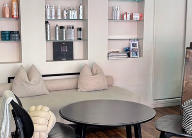 Cozy waiting area at hattieXhair, Worcester, England, GB, featuring plush seating and product display.