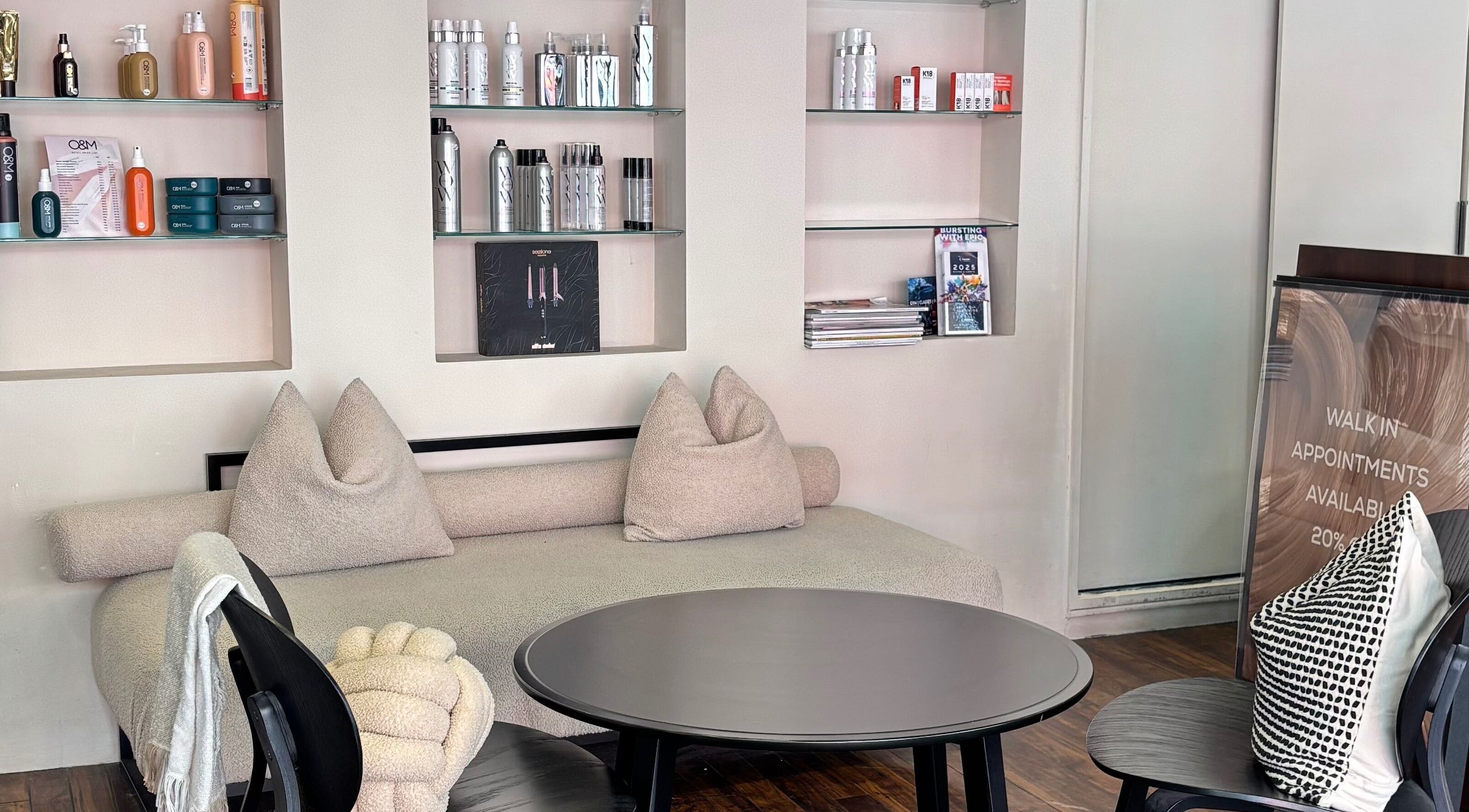 Cozy waiting area at hattieXhair, Worcester, England, GB, featuring plush seating and product display.