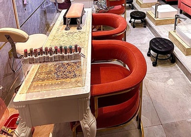 Luxurious nail care station at GIGI BEAUTY CENTER, Dubai, with plush red chairs and nail polish display.