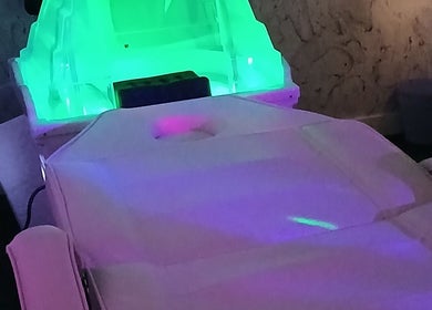 Relaxing spa bed at Solace Head Spa, Llandudno, Wales, GB, illuminated by calming green and purple lights.