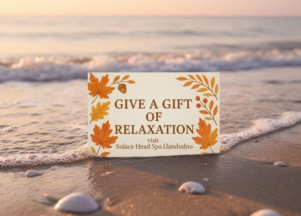 Gift card at shoreline reading 'Give a Gift of Relaxation' for Solace Head Spa, Llandudno, Wales, GB.