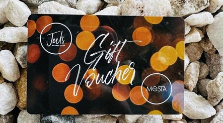 Gift voucher from JOELS Barber Shop | Eastville, Toowoomba, placed on rocks in East Toowoomba, Queensland, AU.