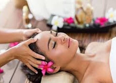 Woman enjoying a head massage at The Beauty Lounge, Maputo, Maputo, MZ with tropical flowers around.