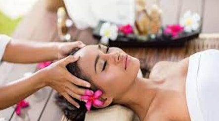 Woman enjoying a head massage at The Beauty Lounge, Maputo, Maputo, MZ with tropical flowers around.