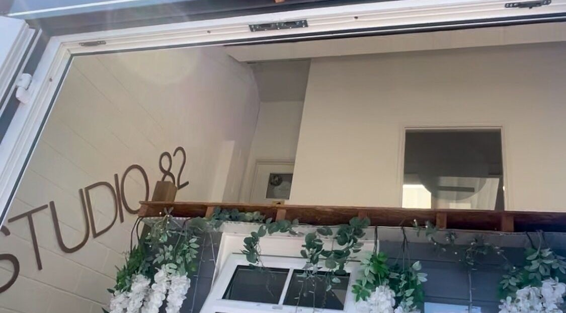 Entrance of JL Beauty in Pontyclun, Wales, GB with 'Studio 82' signage and floral decor.