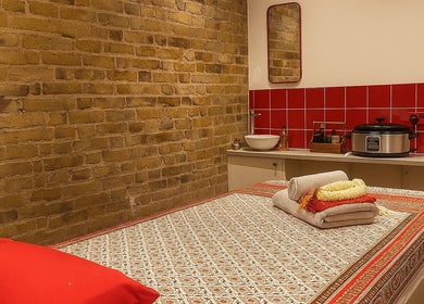Cozy massage room at Even Thai Spa, London, England, GB with a red-tiled wall and comfortable massage table.