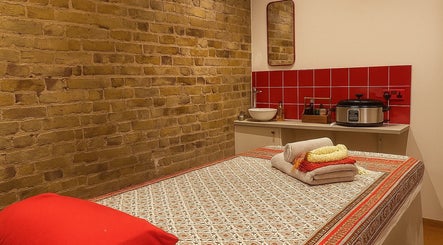 Cozy massage room at Even Thai Spa, London, England, GB with a red-tiled wall and comfortable massage table.